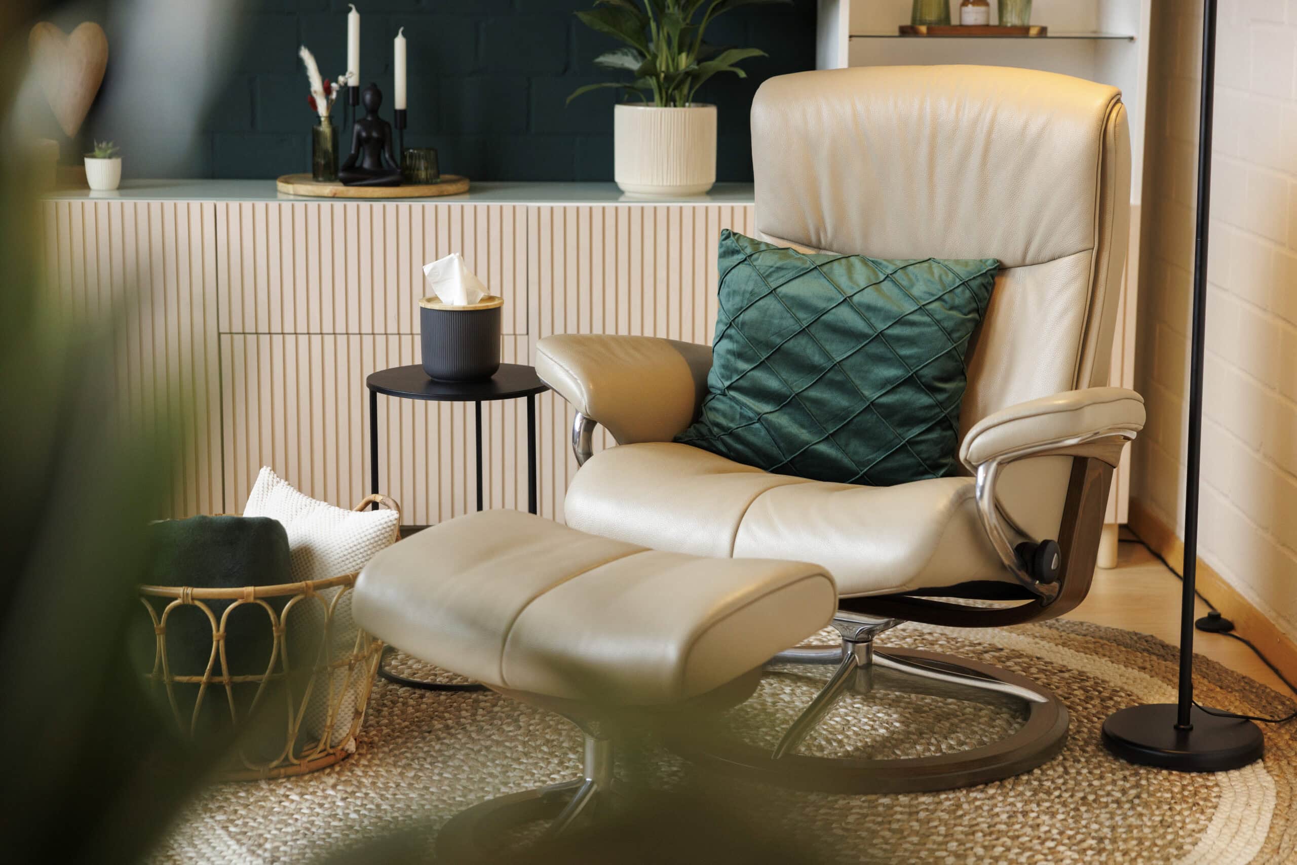 Komfortabler Sessel mit grünen Kissen und Hocker.